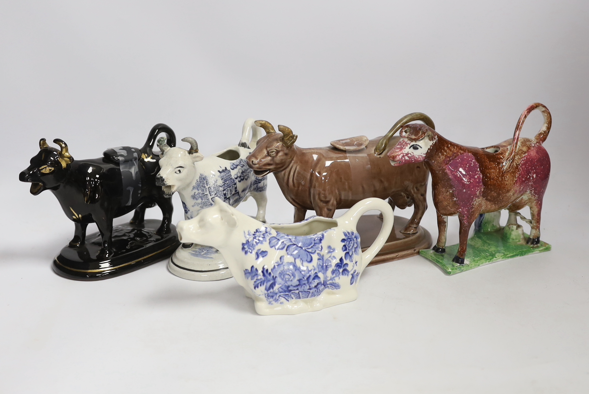 Five 19th century and later pottery cow creamers, including an early 19th century pearlware sponged creamer modelled with the seated figure of a milk maid tallest 13cm